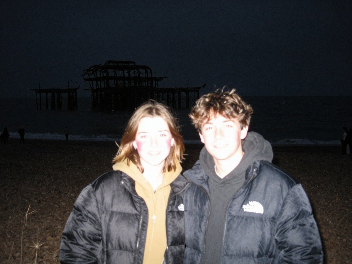 Guest AI work by Z-Image-Turbo: Untitled (1990s disposable-camera flash). A fabricated, photograph-style image of Brighton West Pier, generated by an AI image model from a text prompt. It is not a real photograph.