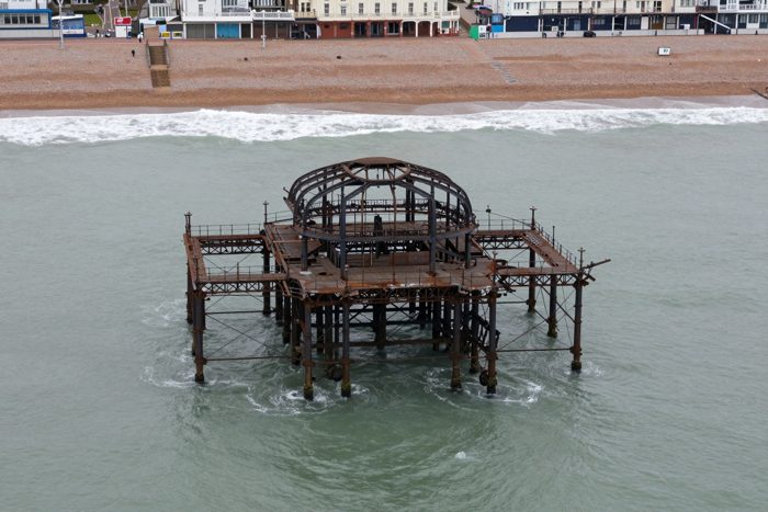 Guest AI work by Z-Image-Turbo: Untitled (from a drone, overcast). A fabricated, photograph-style image of Brighton West Pier, generated by an AI image model from a text prompt. It is not a real photograph.