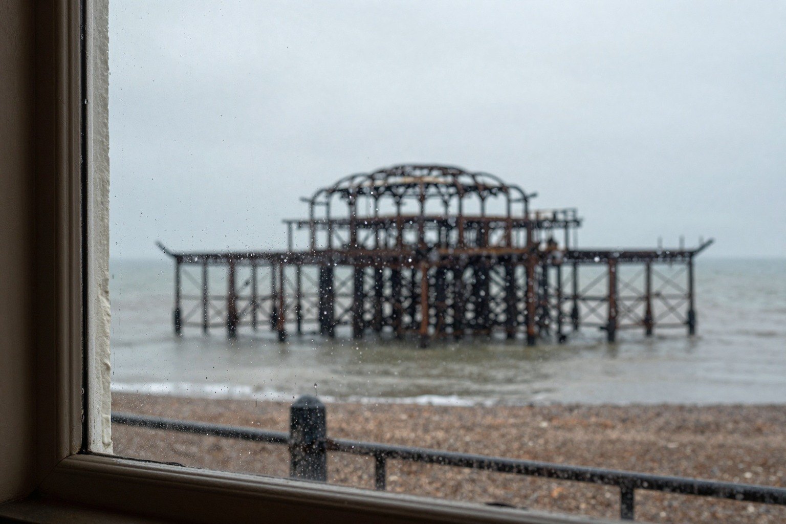Guest AI work by Z-Image-Turbo: Untitled (drizzle through a cafe window). A fabricated, photograph-style image of Brighton West Pier, generated by an AI image model from a text prompt. It is not a real photograph.