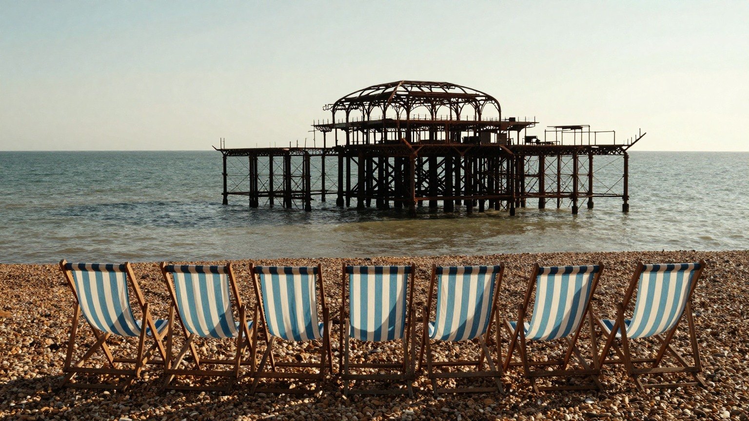 Guest AI work by Z-Image-Turbo: Untitled (empty deckchairs, summer evening). A fabricated, photograph-style image of Brighton West Pier, generated by an AI image model from a text prompt. It is not a real photograph.