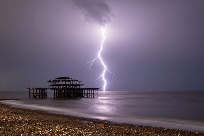 Guest AI work by Z-Image-Turbo: Untitled (forked lightning over the ruin). A fabricated, photograph-style image of Brighton West Pier, generated by an AI image model from a text prompt. It is not a real photograph.